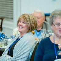 Two alumnae smile as they listen to the speaker present at the Reunion Dinner.